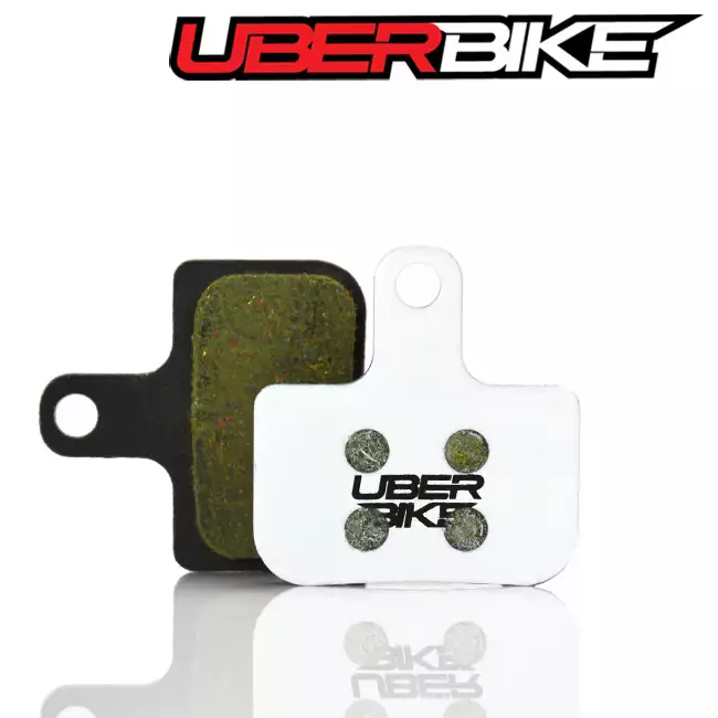 White disc brake pads for SRAM DB Level, with the Uberbike logo in black across the middle of them.