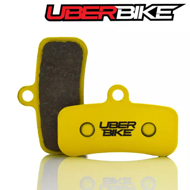 Yellow Sintered Uberbike disc brake pads for Shimano Saint with the Uberbike logo in black across the middle of them